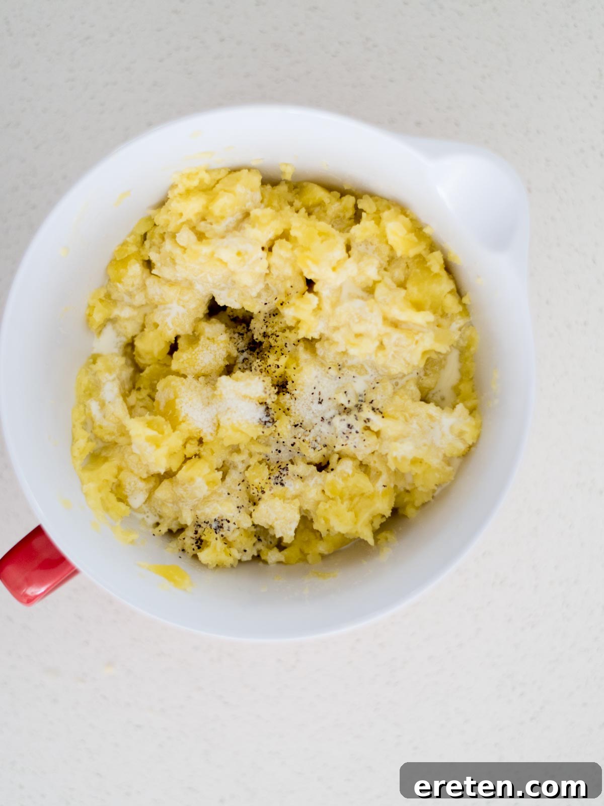 Mixing bowl with seasoning added to the potatoes and butter as its being mashed.