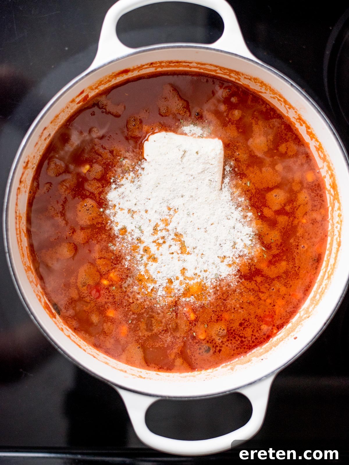 Cream cheese and dry ranch seasoning added to the simmering tomato and bean mixture in a dutch oven.