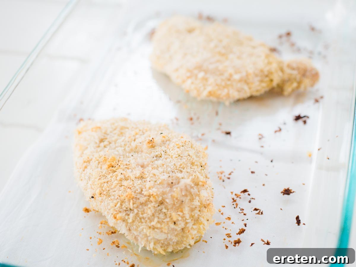 Close-up of a golden brown, breaded baked chicken breast, showcasing its crispy texture.