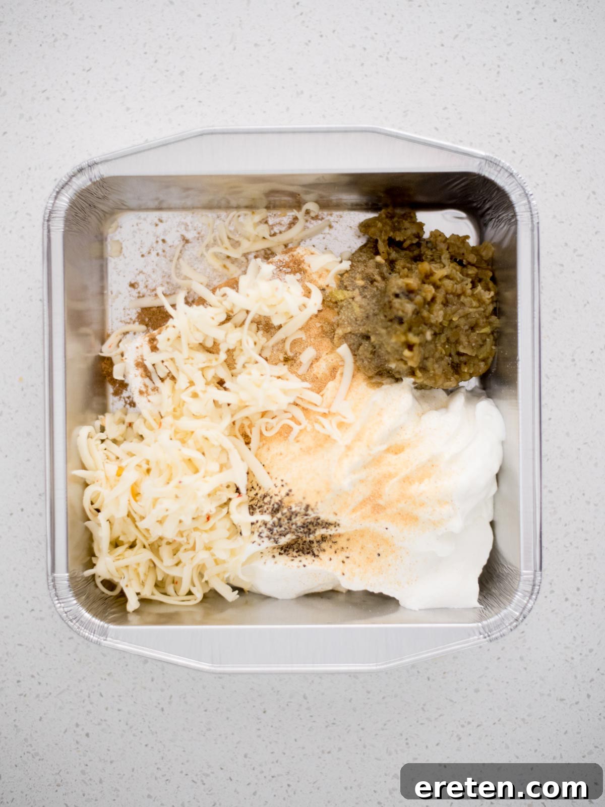 All the measured ingredients for smoked queso blanco placed in a baking dish, ready to be mixed.