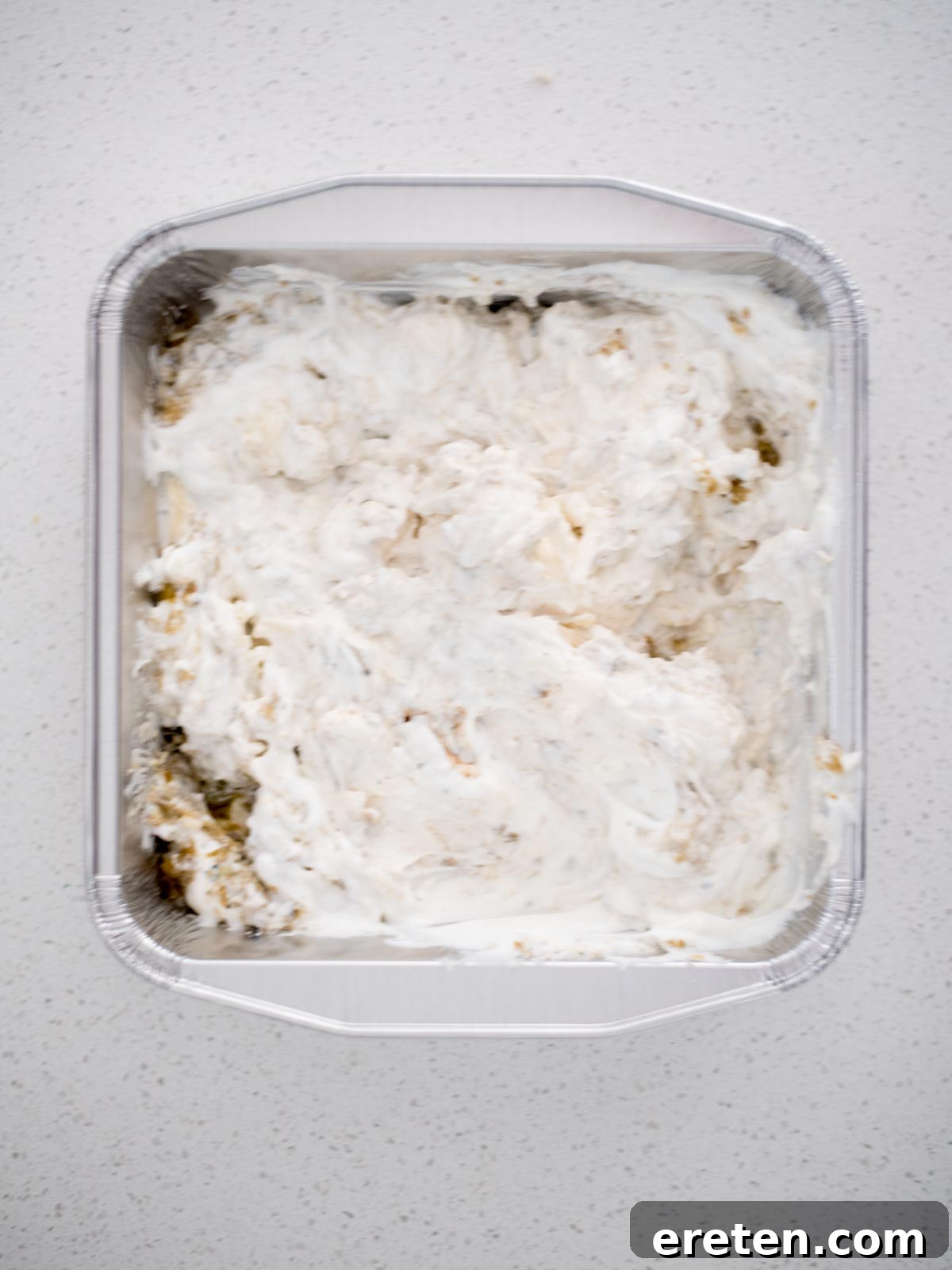 The smoked queso blanco ingredients thoroughly mixed together in an aluminum pan, showcasing a creamy base.