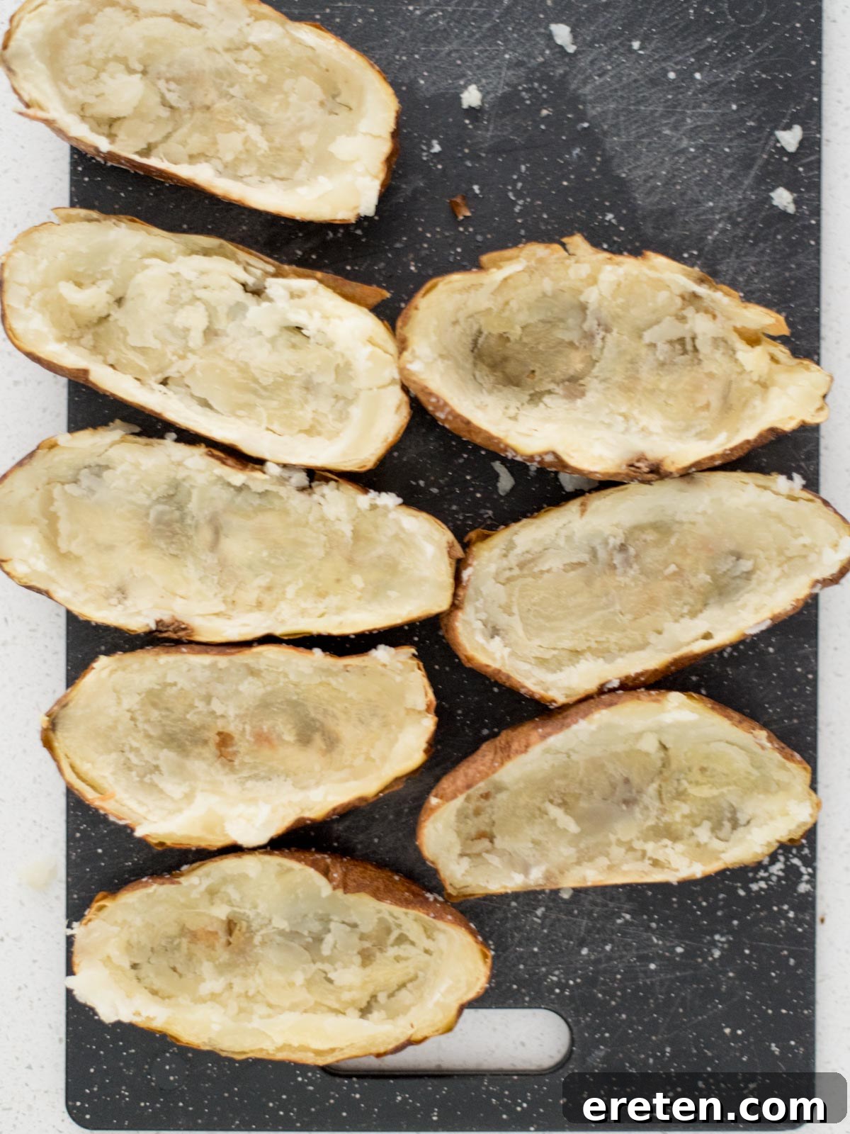 Potato skins on a cutting board with the potatos removed from the middle.