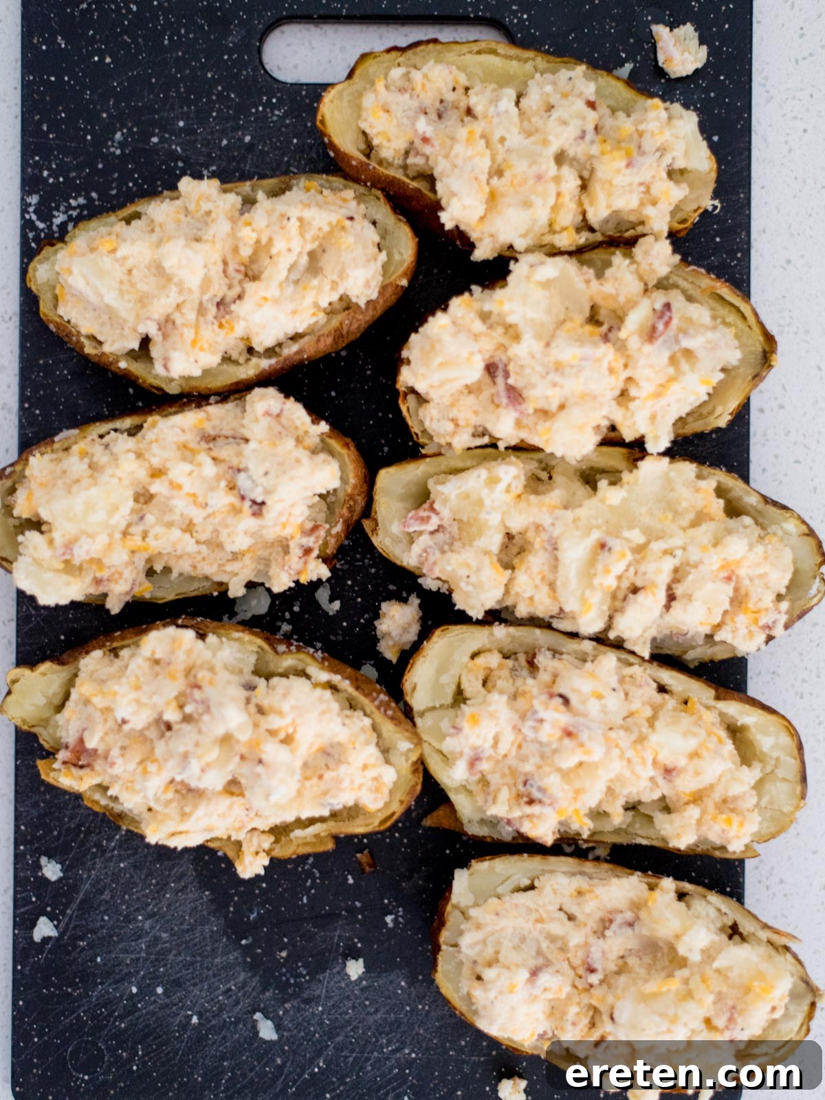 Twice baked potatoes sitting on a cutting board with the potato mixture added back in.