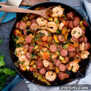 Cajun Fire Skillet with Shrimp and Sausage 10 Scoop of cajun shrimp, sausage and vegetables on a wooden spoon in a cast iron pan.