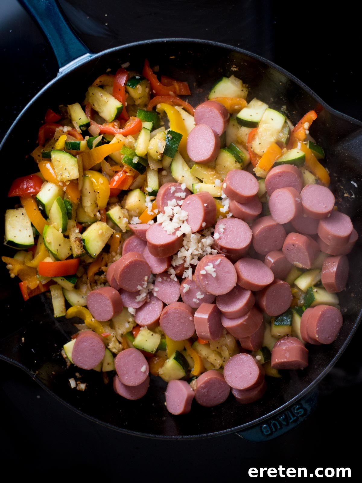 Cajun Fire Skillet with Shrimp and Sausage 7 Raw cut up veggie and sausage pieces with a splash of broth inside a cast iron skillet.
