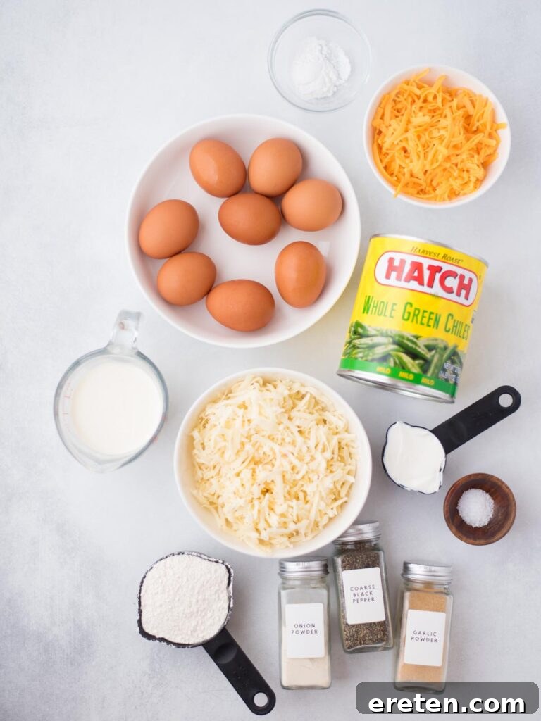 A vibrant display of fresh ingredients laid out, including eggs, milk, sour cream, flour, spices, green chiles, and two types of shredded cheese, ready to be prepared for the Hatch Chile Relleno Casserole.