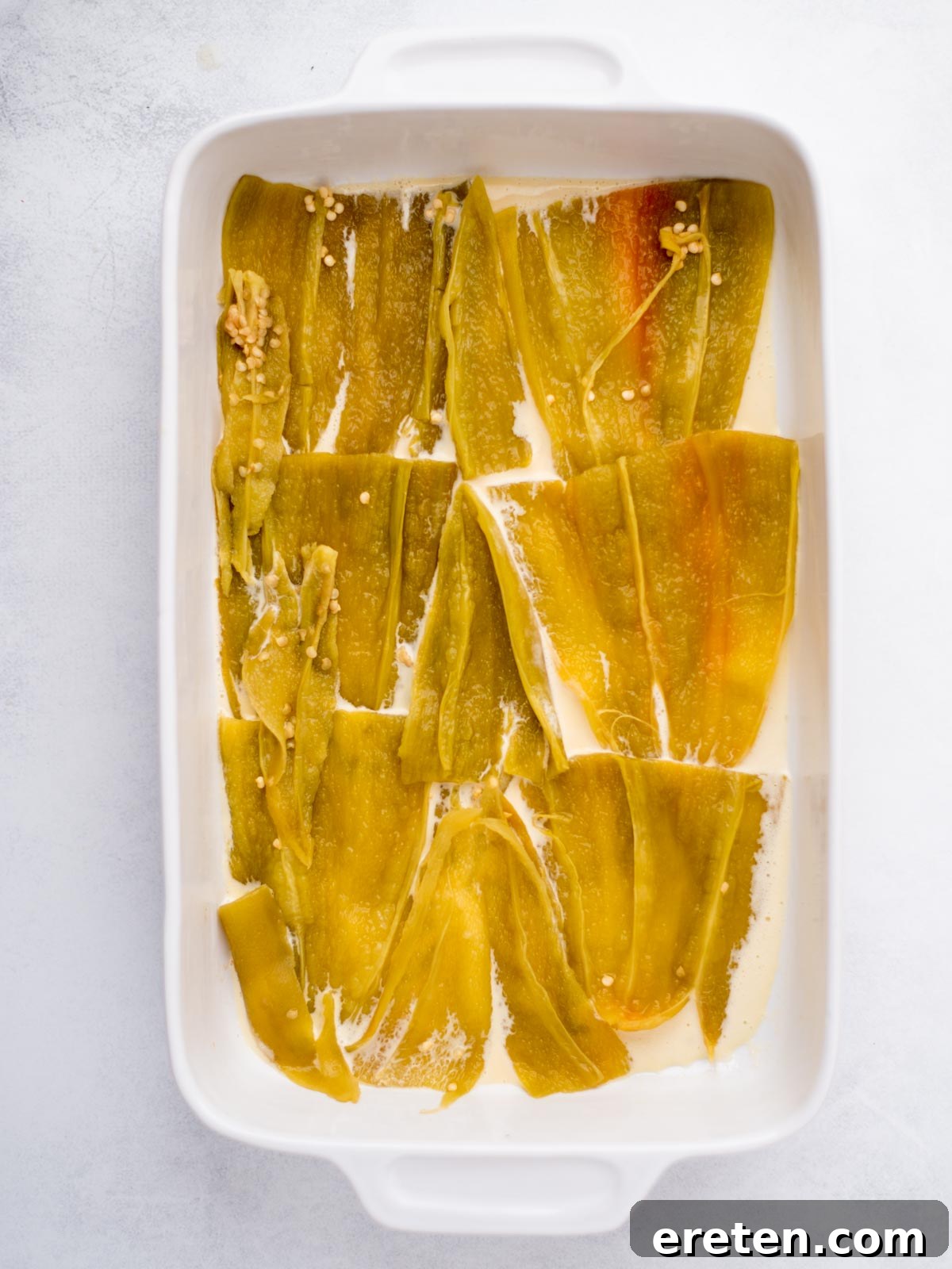 Hatch chiles added to the baking dish over the egg mixture, forming the first layer.