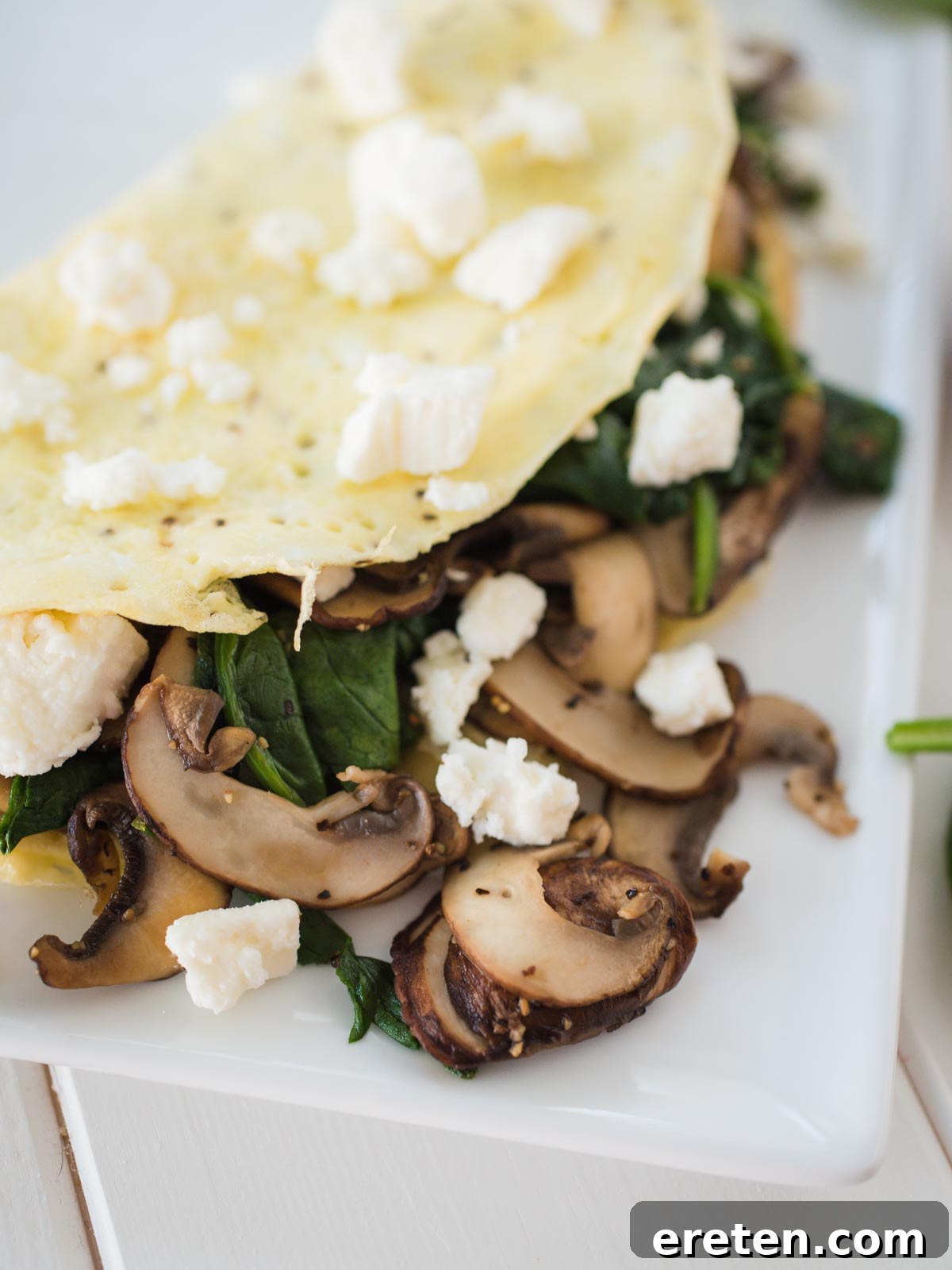 Delicious and Fluffy Spinach Mushroom Feta Omelet on a white plate with a fork