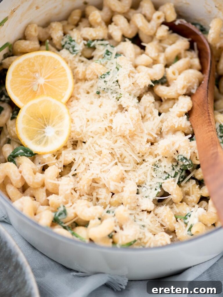 Wooden spoon in the dutch oven lemon ricotta pasta with lemon slices on top.