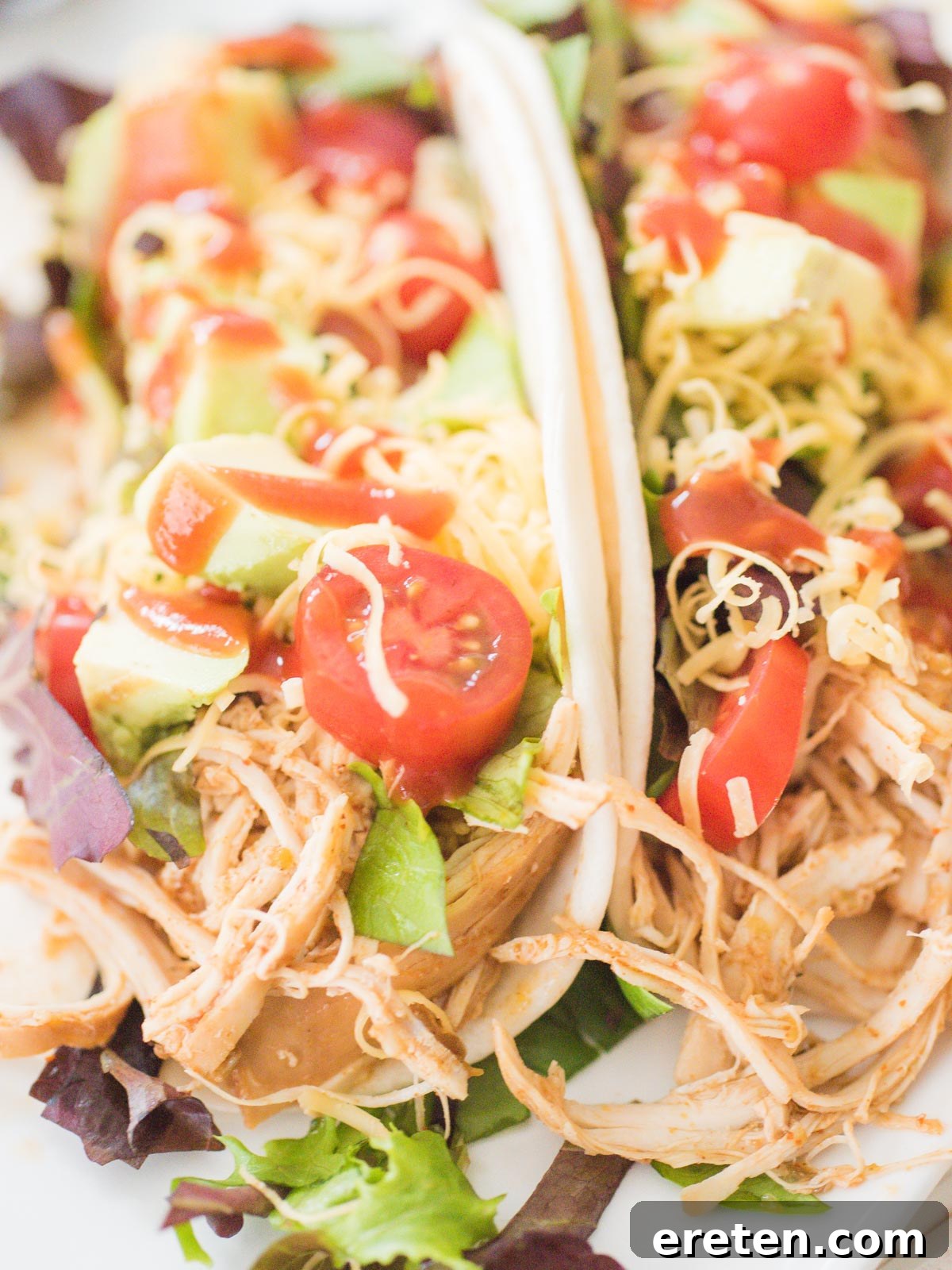 crockpot chicken tacos on a white plate with toppings