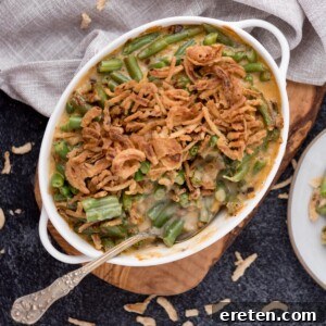 Spoon laying in a baking dish of air fryer green bean casserole topped with french's fried onions.