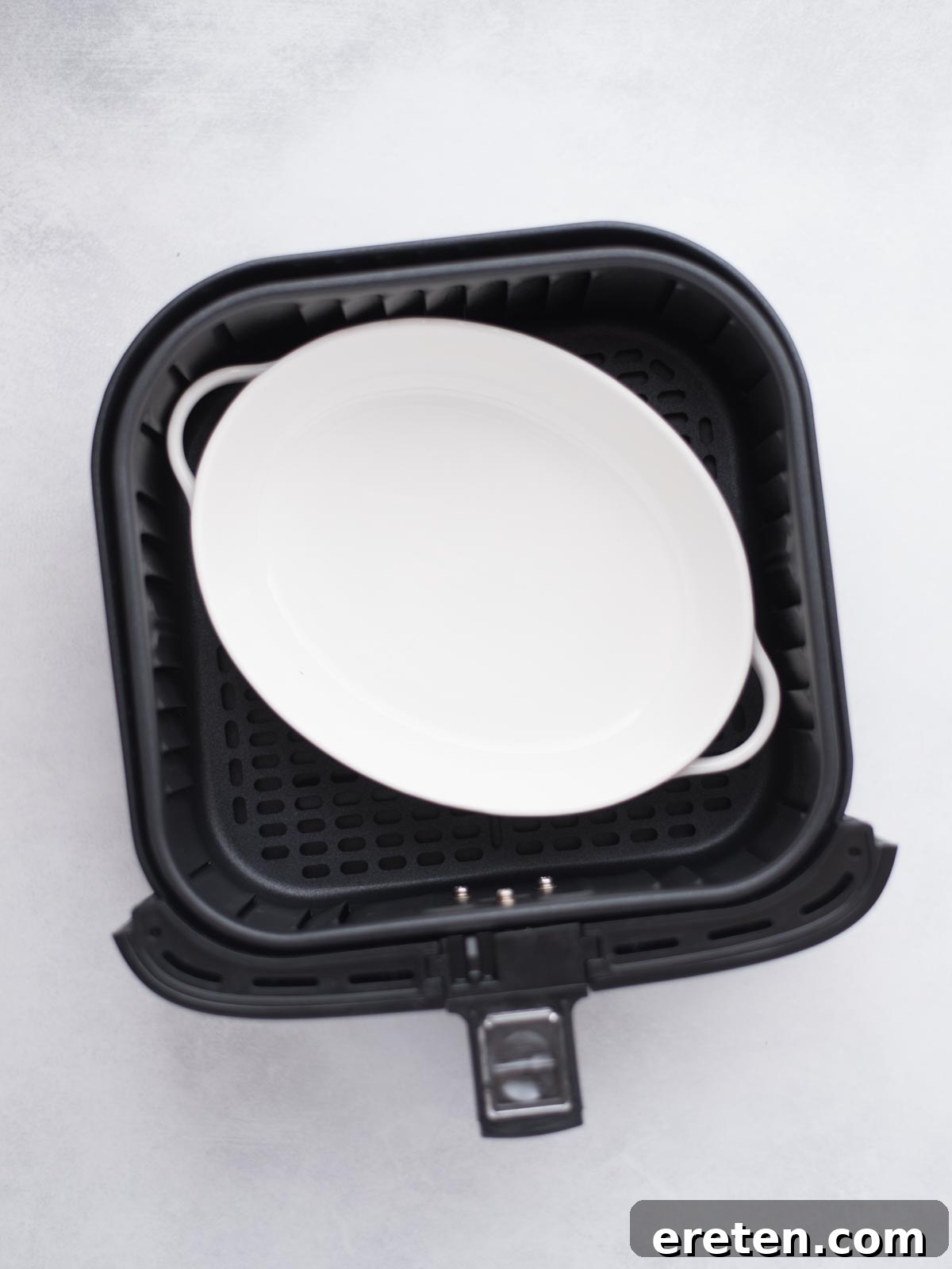 Empty baking dish sitting in the air fryer bucket.