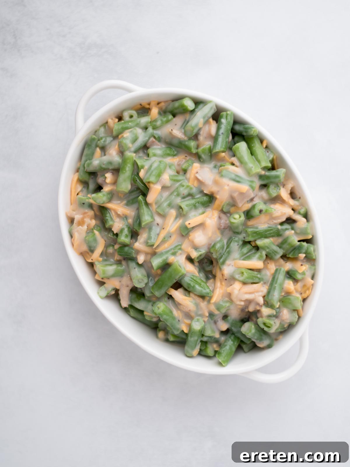 White baking dish filled with uncooked green bean casserole.