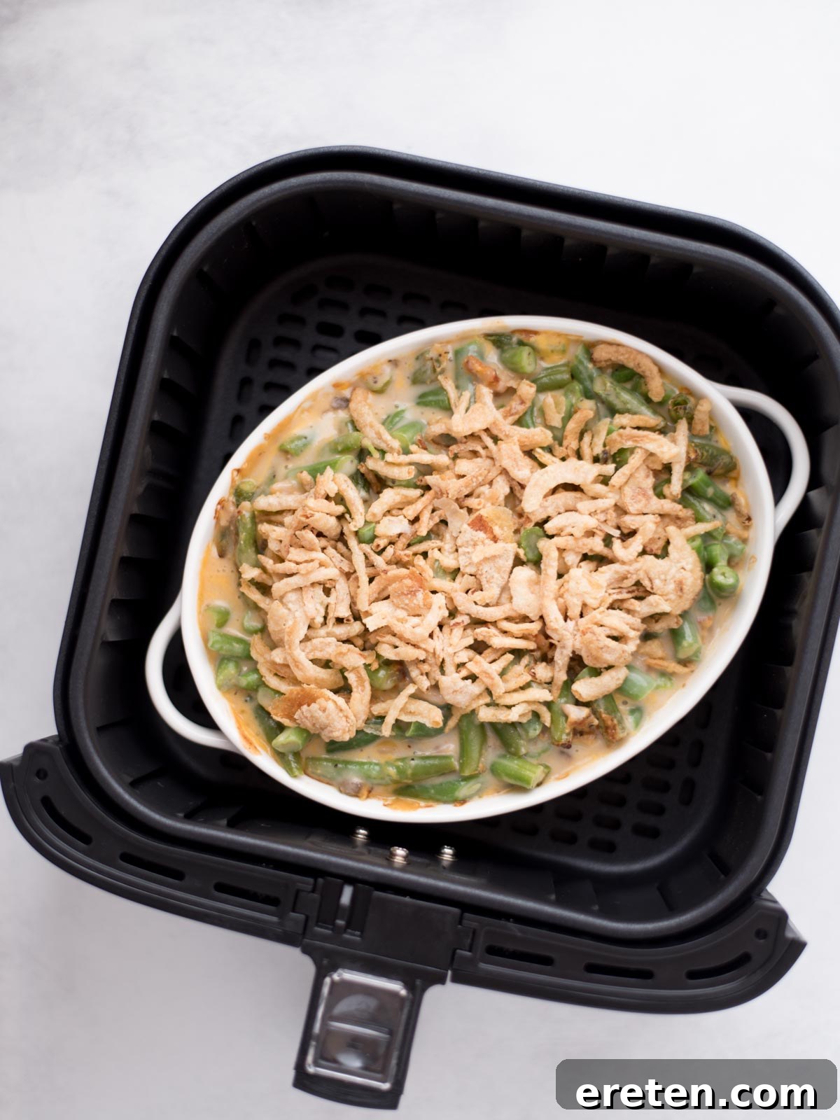 French's fried onions topped over the green bean casserole in the air fryer bucket.