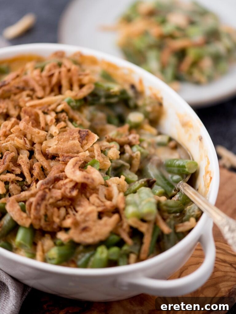 Scoop removed from air fryer green bean casserole baking dish and a spoon laying in the pan.