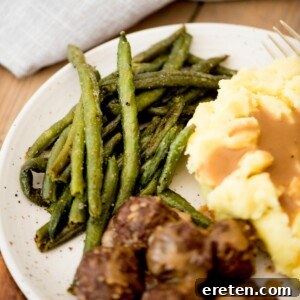 A side serving of perfectly roasted frozen green beans on a plate, complementing a hearty meal.