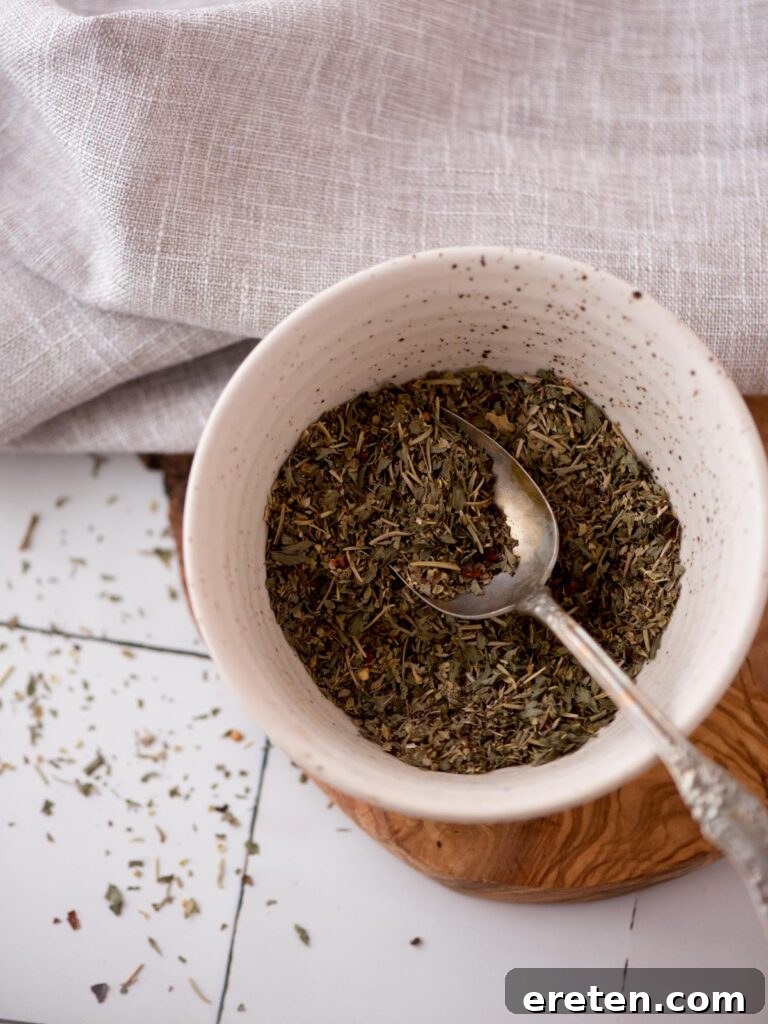 Italian seasonings combined in a small bowl with a teaspoon in it.