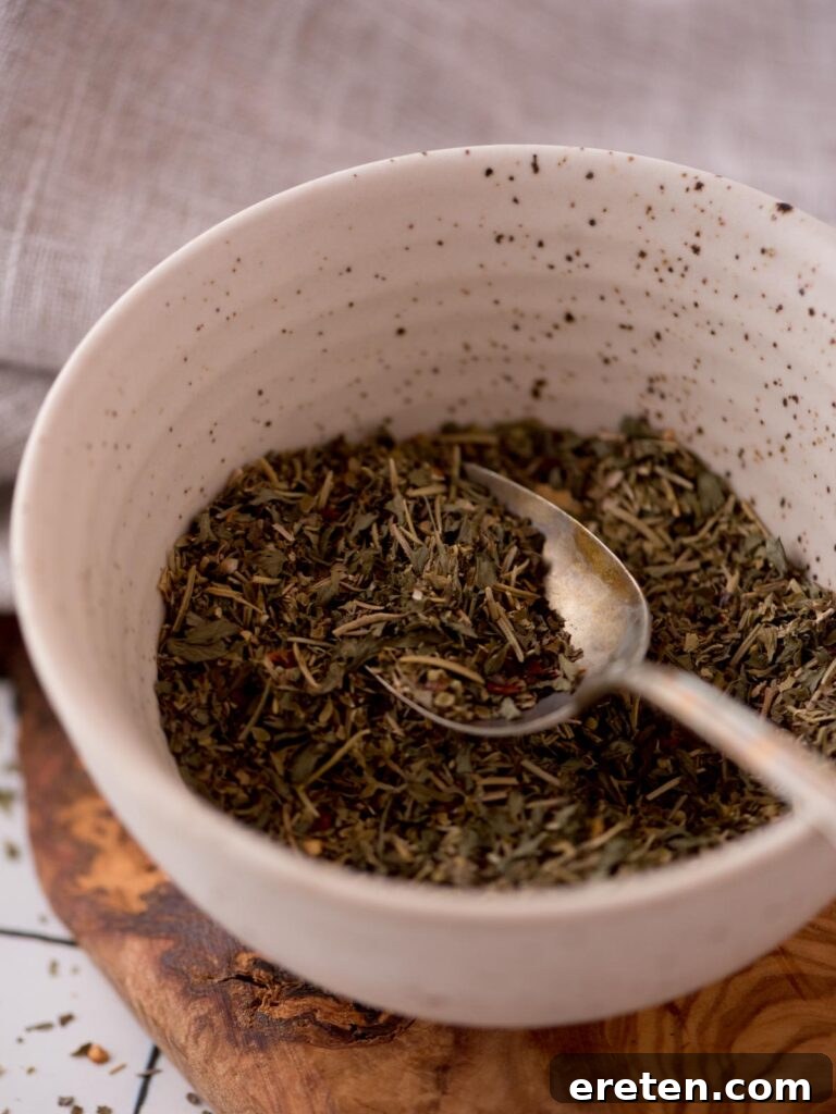 Spoon of homemade italian seasoning in a bowl.
