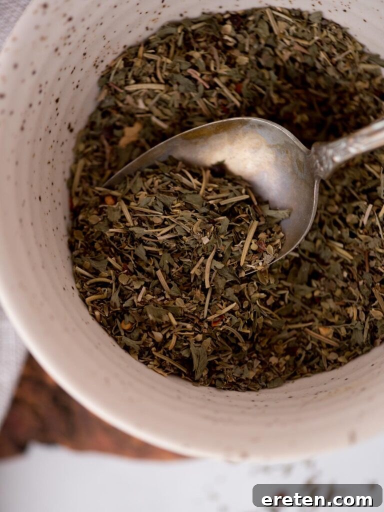 top view of homemade italian seasonings in a bowl with a spoon tucked in.