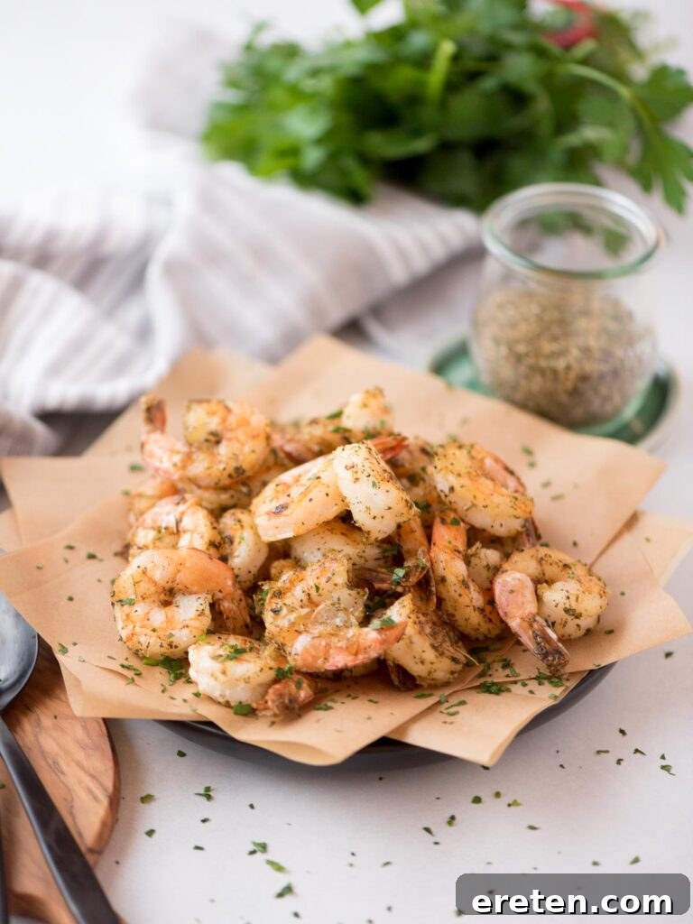 Crispy Air Fryer Frozen Shrimp 2 Crispy air fryer frozen seasoned shrimp elegantly arranged on a parchment paper-lined plate, ready to be served.