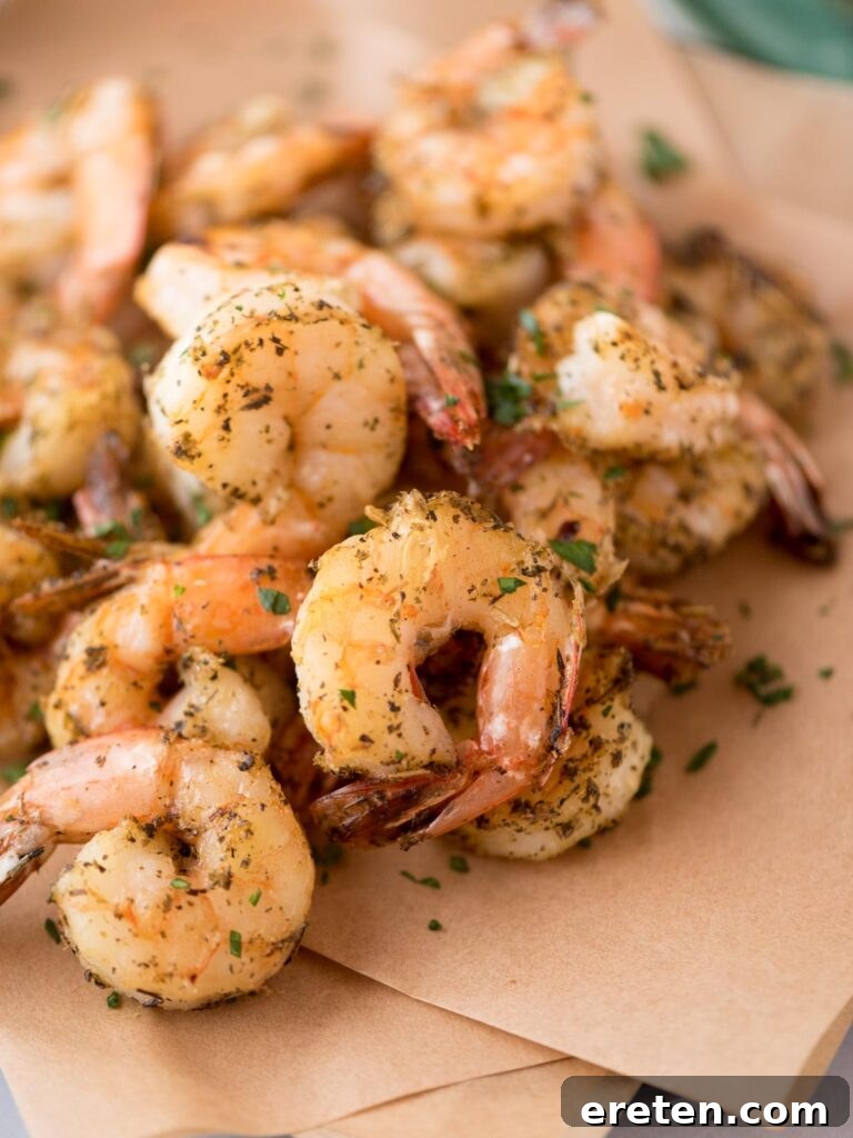 Crispy Air Fryer Frozen Shrimp 8 Platter of perfectly cooked air fryer shrimp resting on parchment paper, ready to be enjoyed.