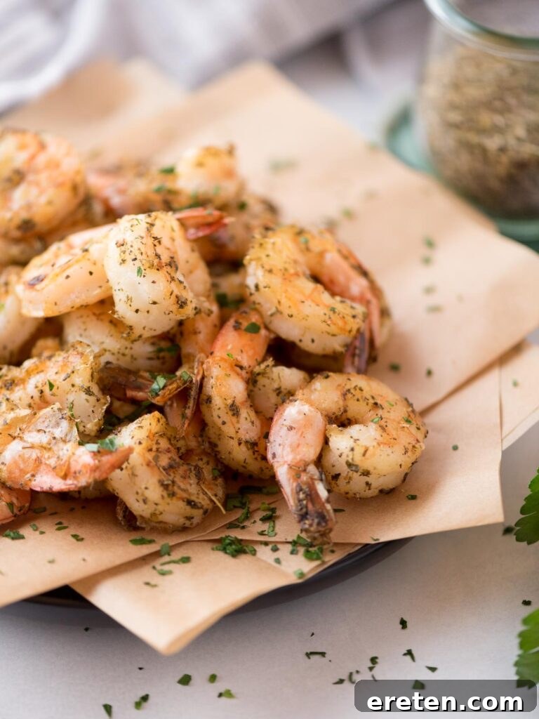 Crispy Air Fryer Frozen Shrimp 9 Air fryer frozen seasoned shrimp, beautifully presented on a parchment paper-covered plate, garnished and ready to serve.