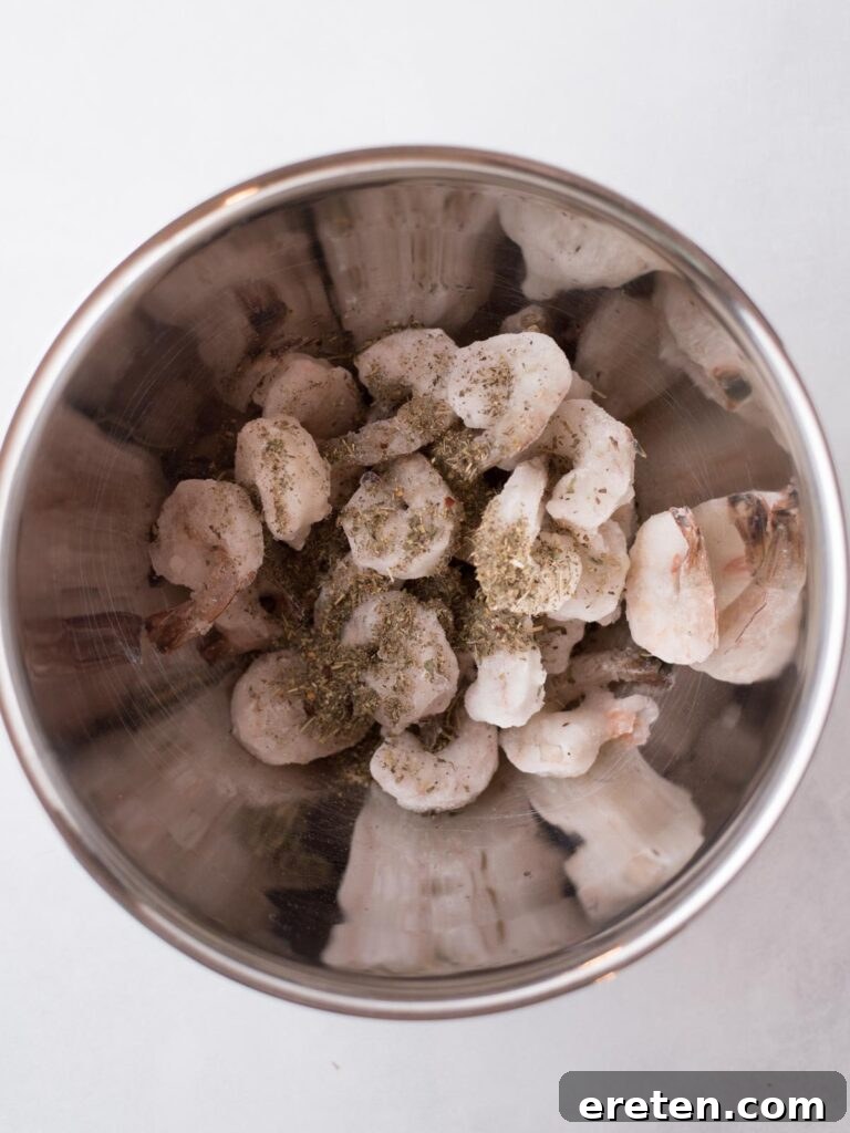 Crispy Air Fryer Frozen Shrimp 4 Frozen shrimp in a mixing bowl being tossed with seasoning, ensuring an even coating.
