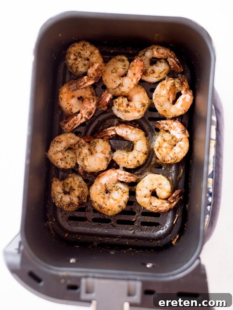 Crispy Air Fryer Frozen Shrimp 7 Perfectly cooked and seasoned shrimp inside an air fryer basket, showcasing their golden-brown finish.