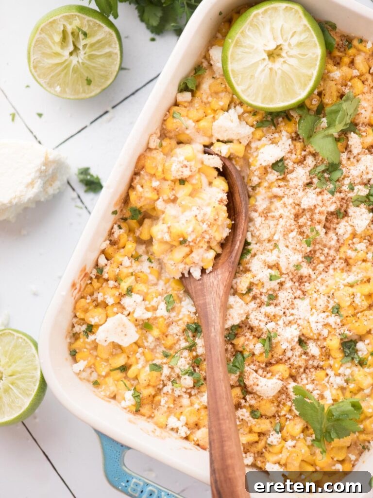 Fiesta Corn Bake 2 Wooden spoonful of street corn casserole in a baking dish, showcasing its creamy texture and fresh cilantro garnish.