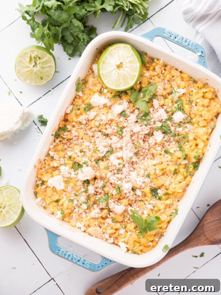 Fiesta Corn Bake 9 Mexican street corn casserole in a baking dish, garnished with a lime wedge and cilantro, ready to serve.