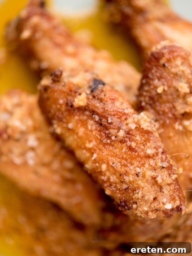 Air-Fried Golden Garlic Parmesan Wings 13 Stacked garlic parmesan chicken wings on a light blue plate, ready to be served