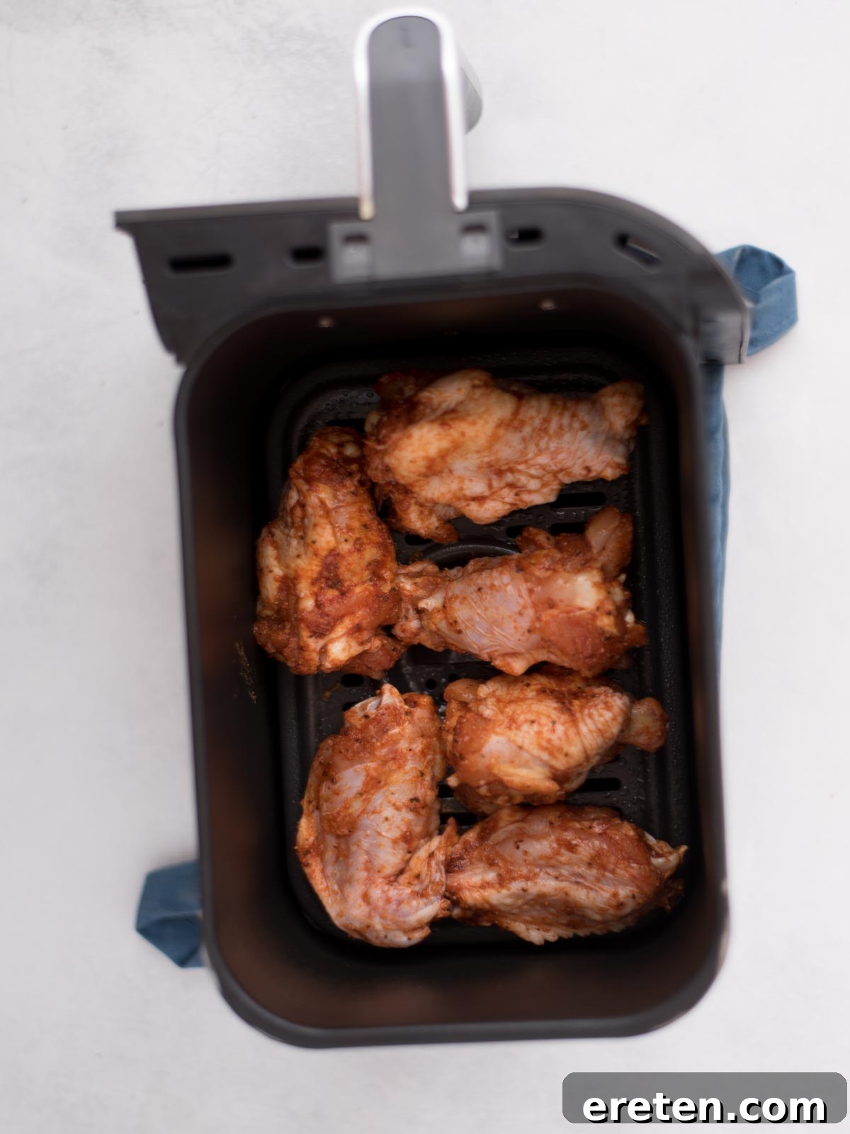 Air-Fried Golden Garlic Parmesan Wings 5 Seasoned chicken wings arranged in a single layer inside an air fryer basket, ready for cooking