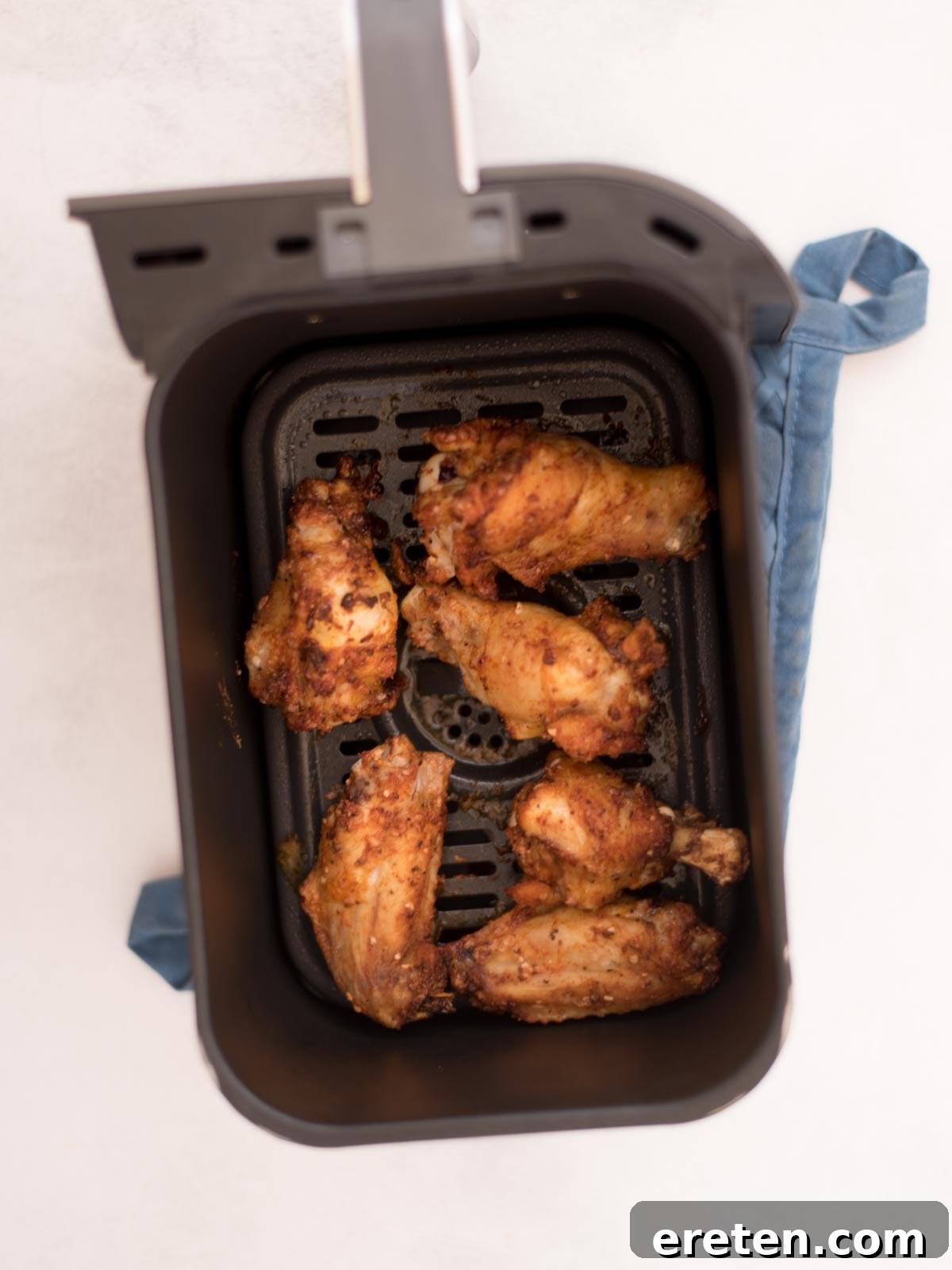 Air-Fried Golden Garlic Parmesan Wings 6 Partially cooked seasoned chicken wings inside an air fryer basket, showing browning