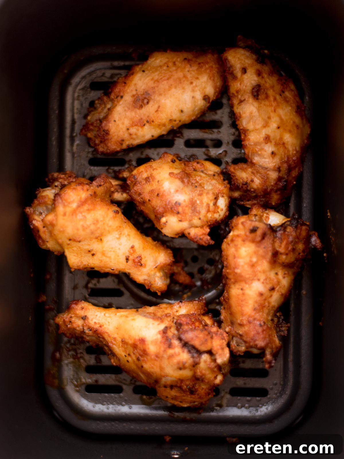 Air-Fried Golden Garlic Parmesan Wings 7 Crispy cooked chicken wings inside an air fryer basket, golden brown and ready to be sauced