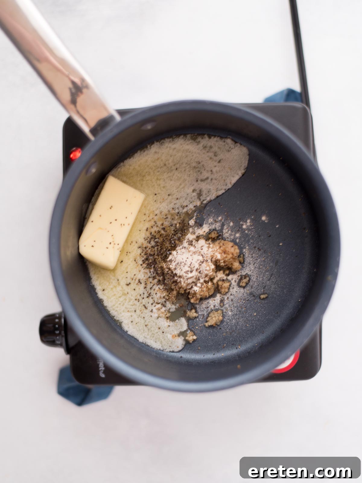 Air-Fried Golden Garlic Parmesan Wings 8 Butter, fresh garlic, onion powder, and black pepper in a saucepan before melting, showing the raw ingredients for the sauce