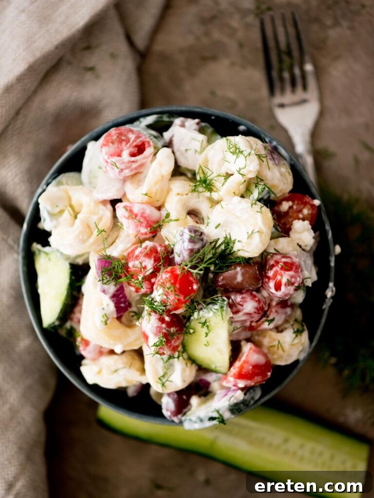 Mediterranean Tortellini Pasta Salad 2 A vibrant bowl of Greek Tortellini Pasta Salad topped with fresh dill, ready to be served at a summer gathering.