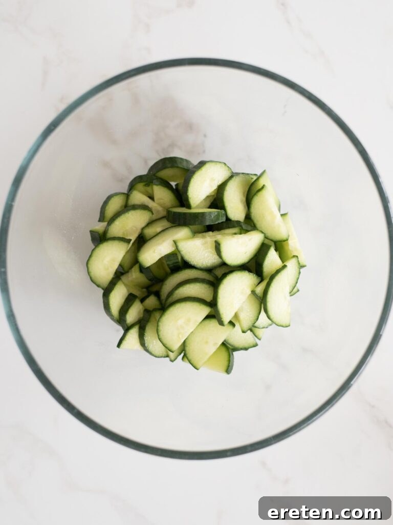 Mediterranean Tortellini Pasta Salad 4 Sliced cucumbers being added to a large mixing bowl.