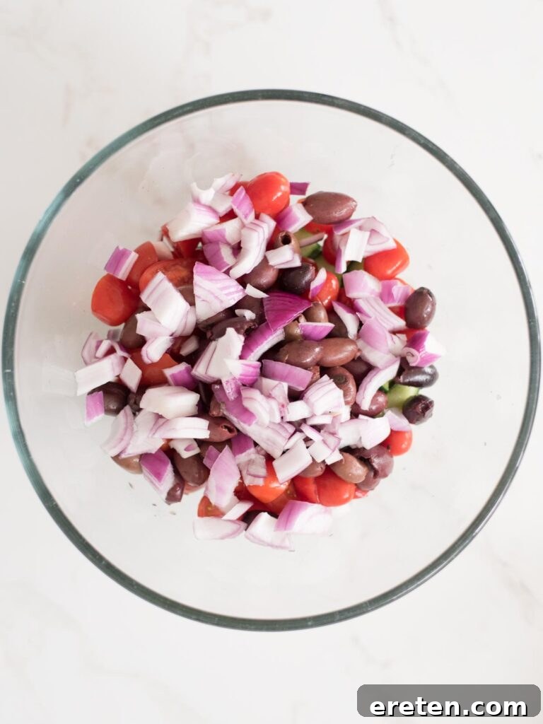 Mediterranean Tortellini Pasta Salad 7 Finely chopped red onion added to the bowl, ready to contribute its sharp flavor.