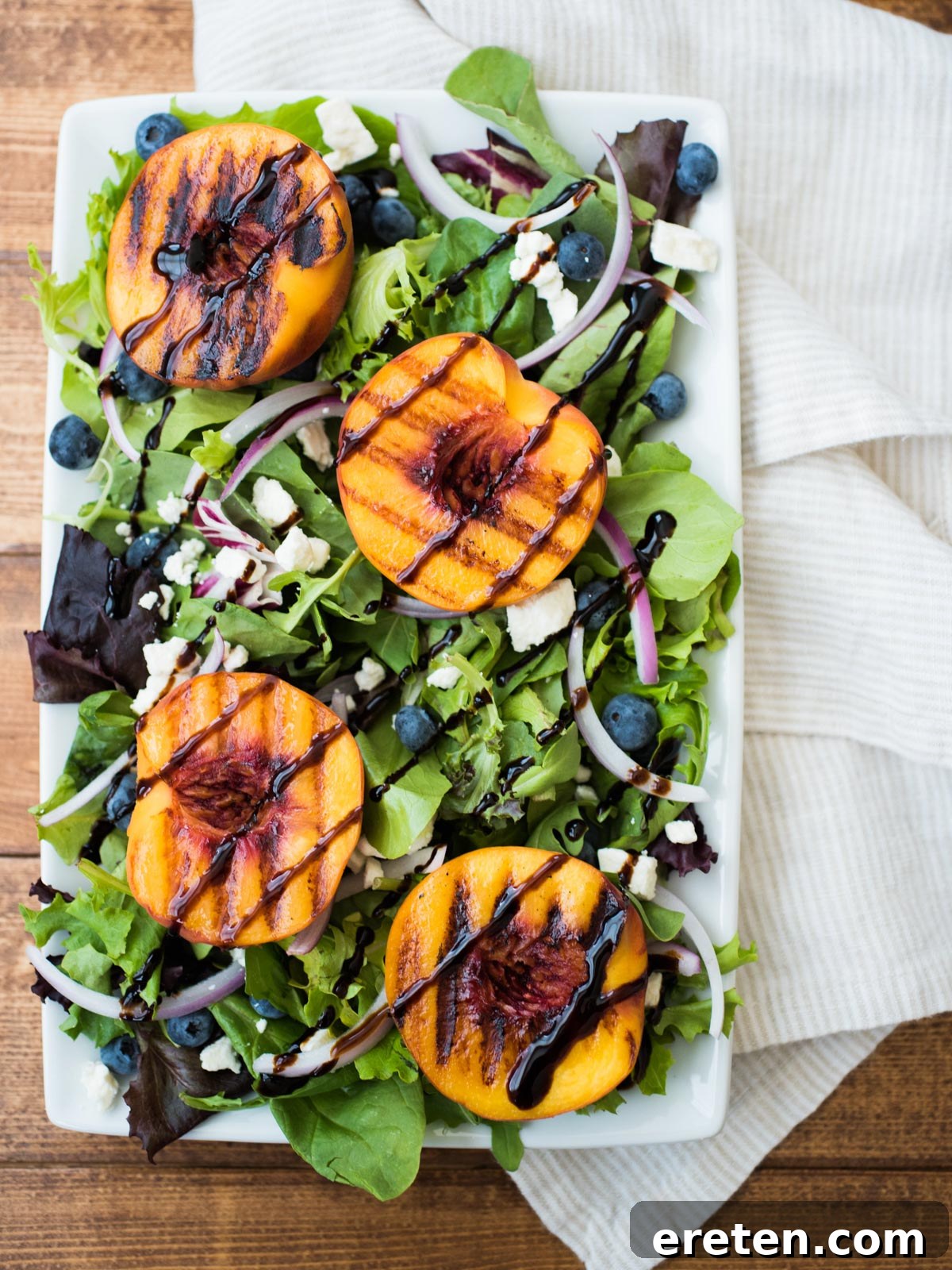 Blistered Peach Summer Salad 2 Vibrant grilled peach salad on a white plate, showcasing fresh ingredients and balsamic glaze