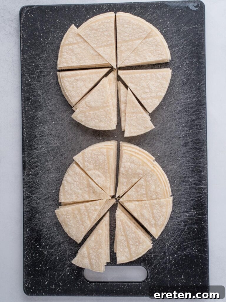 Cutting board with stacks of corn tortillas cut into triangles in preparation for making homemade chips.