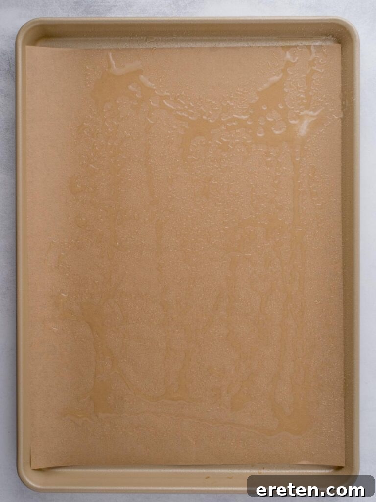 Avocado oil added to a parchment paper topped baking sheet.