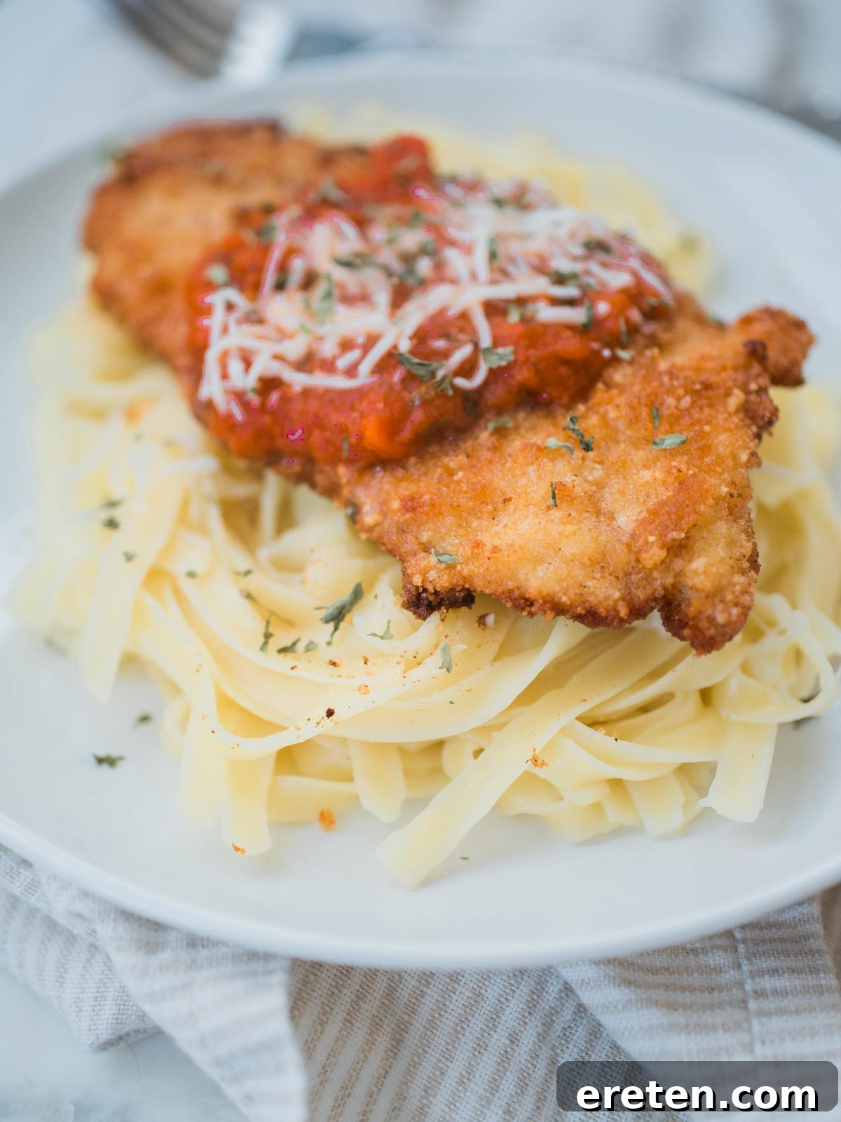 Golden-brown crispy chicken parmesan served over buttered spaghetti with melted mozzarella and marinara sauce. A perfect homemade Italian-American comfort food.