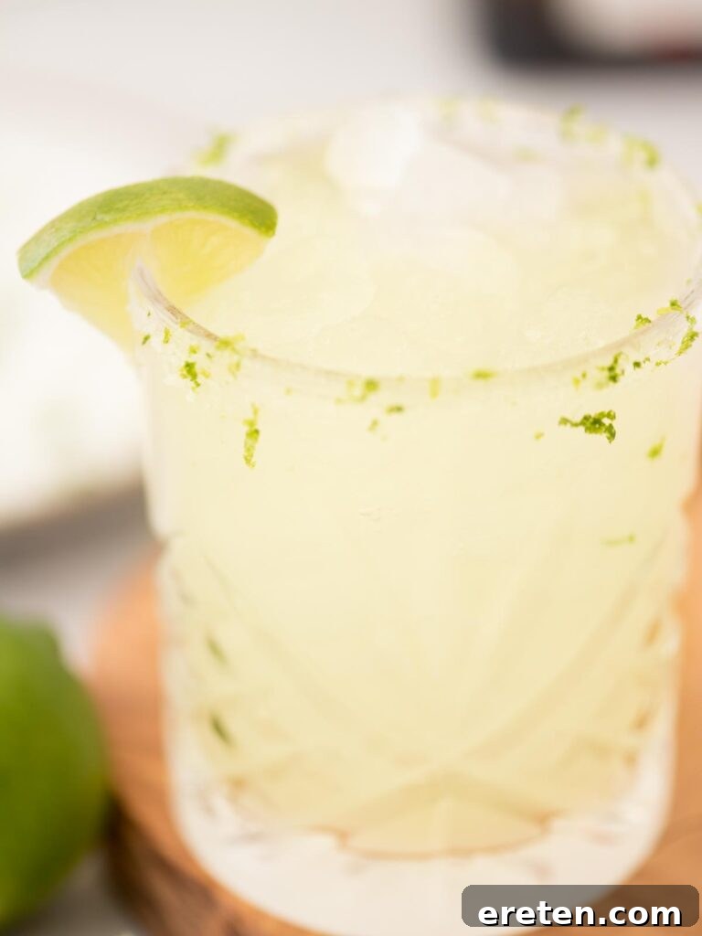 Stone Cold Margarita 5 margarita on the rocks in a salt rimmed glass with a lime wedge and lime zest