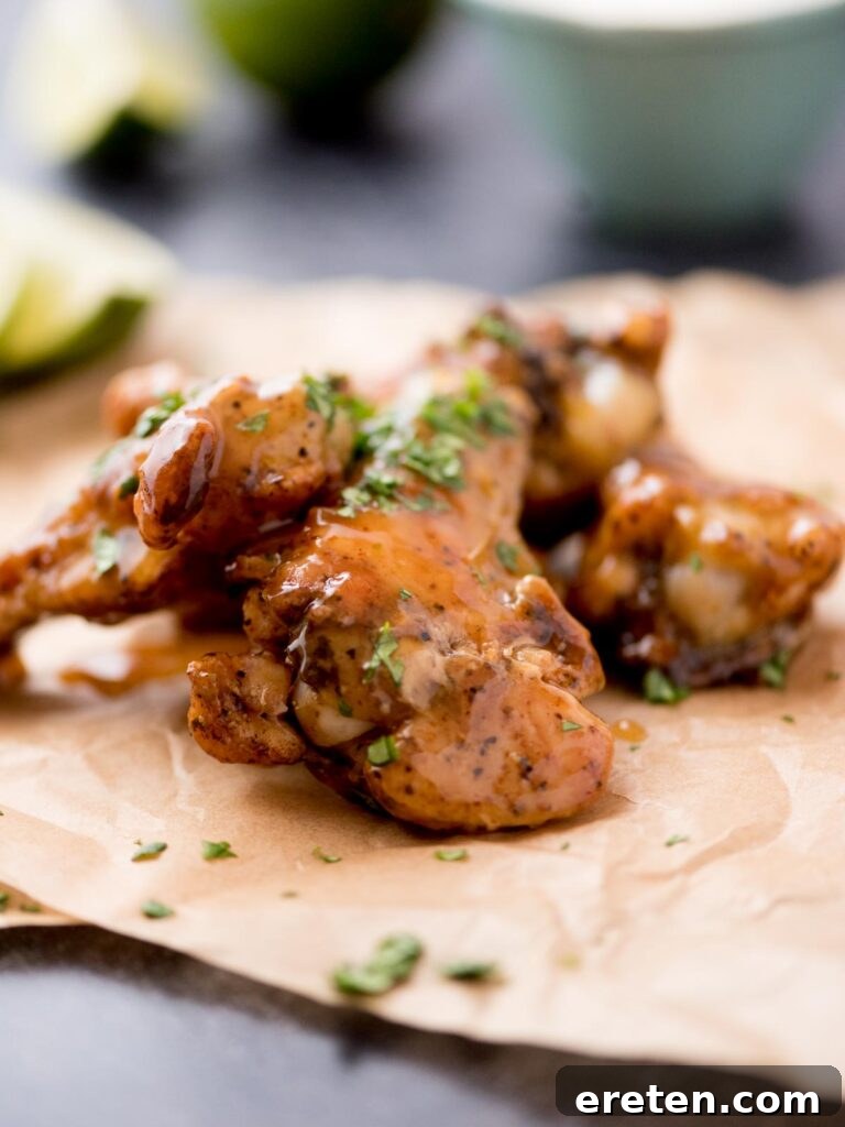 Golden brown tequila lime chicken wings garnished with fresh cilantro on parchment paper, ready to serve.
