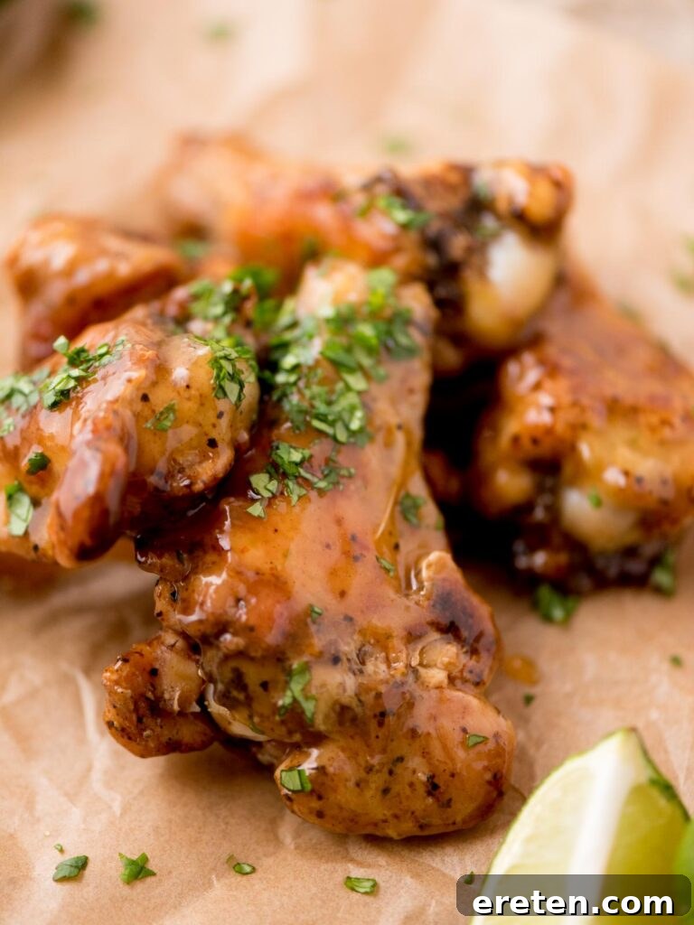 Tequila lime glazed chicken wings with chopped cilantro served on parchment paper with a lime wedge, ready for a feast.