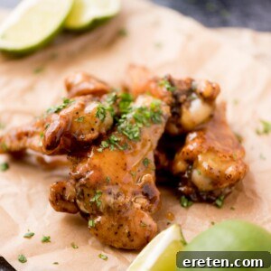 Close up of tequila lime wings with chopped cilantro garnished on top laying on parchment paper.