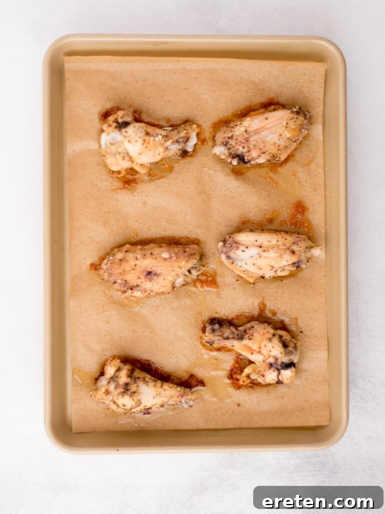 Seasoned chicken wings on a baking sheet, golden and ready for sauce.