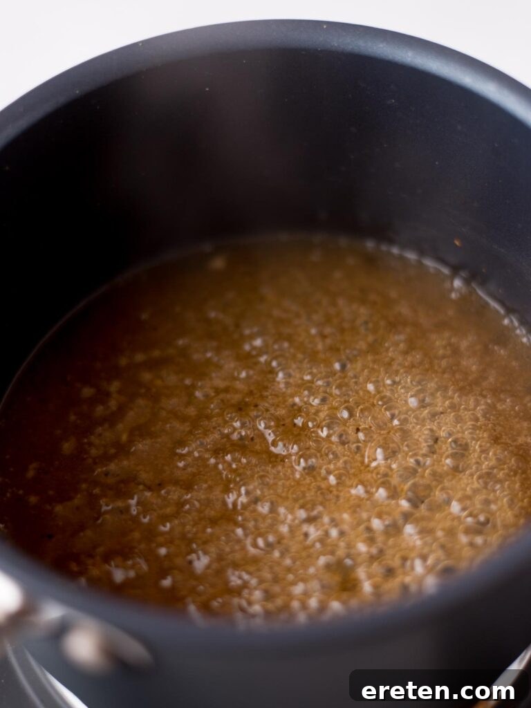 Tequila glaze simmering gently in a saucepan, thickening to a perfect consistency.