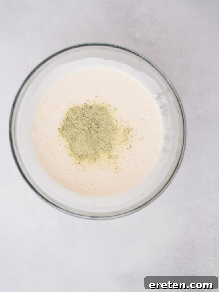 Bold Ranch Kick 5 Dry ranch seasoning mix being poured into the buttermilk and mayonnaise mixture.