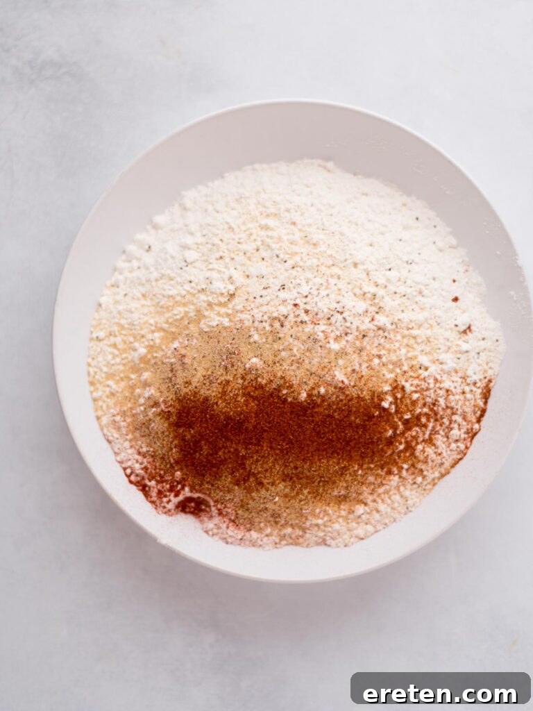 A bowl filled with a perfectly blended mixture of flour and various seasonings, ready to bread the chicken.